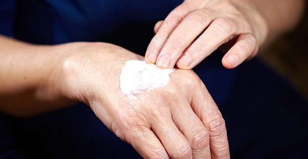 a woman rubs cream on her age spots on her hands