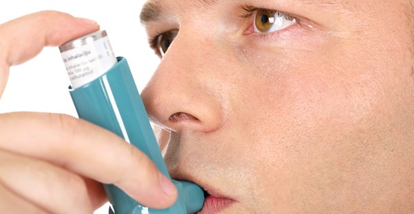 a man uses an inhaler to treat his asthma