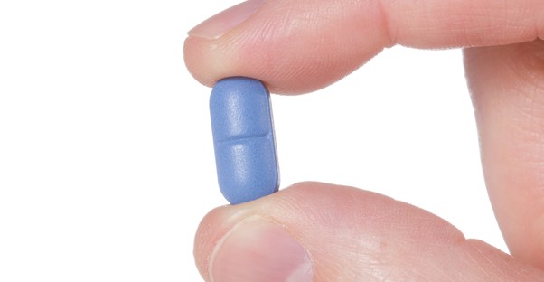 a pill for erectile dysfunction is held between two fingers