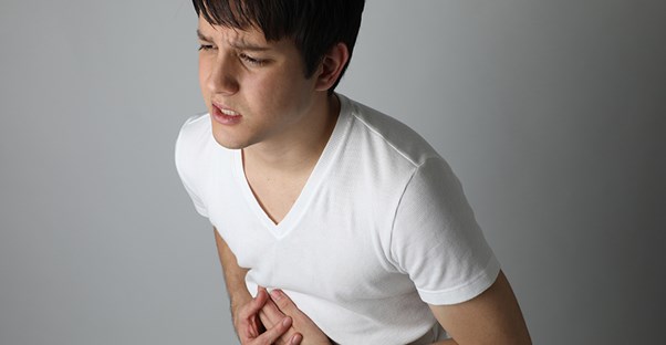 a young man holding his stomach because of ibs or epi