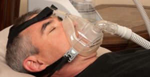 a man sleeps with a sleep apnea machine on his face