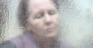 a concept image of a depressed woman who is bipolar behind frosted glass