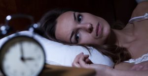 a woman can't sleep in her bed while worrying about mental health wellness