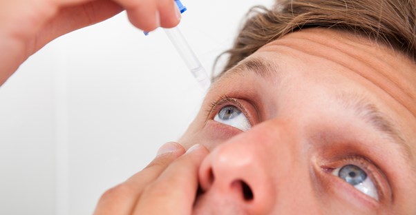 a man uses eye drops as allergy treatments